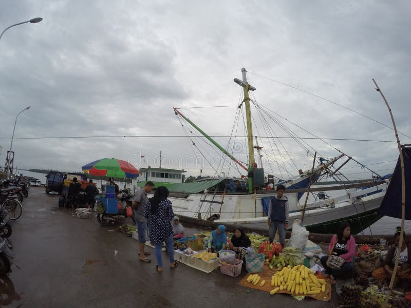 a market on the banks of the Mentaya Borneo river, with a cargo boat in the background