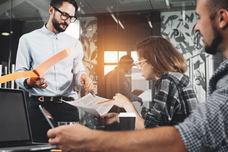 Marketing group discussing new product plan. Young businesspeople working on modern devices. New startup company. Intentional len stock image Marketing group discussing new product plan. Young businesspeople working on modern devices. New startup company. Intentional len stock image