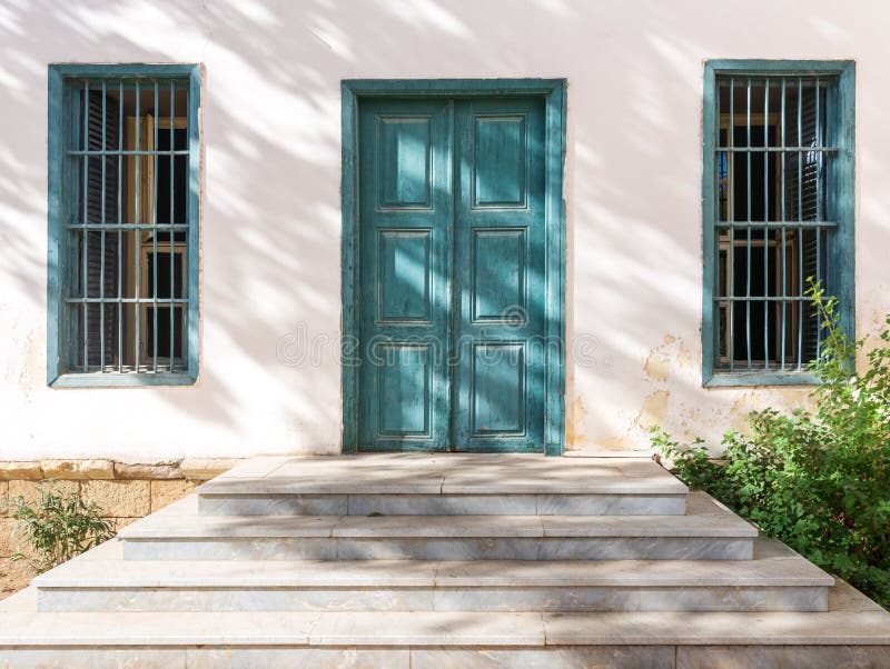 Marmortreppe vor der weißen Wand, alte grüne Holztüre und zwei schmiedeeiserne Fenster stockbild Marmortreppe vor der weißen Wand, alte grüne Holztüre und zwei schmiedeeiserne Fenster stockbild