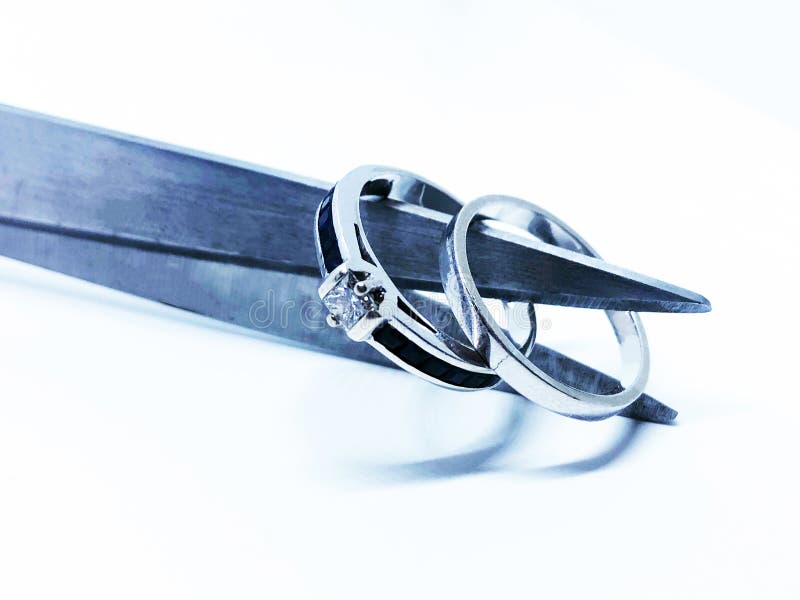 Marriage broken and cut up by divorce. Wedding and engagement ring being cut by scissors. A symbol of divorce and broken marriage stock photography