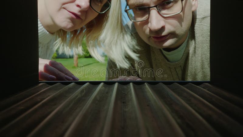 A married couple looks in an empty mail box, upset - no letters