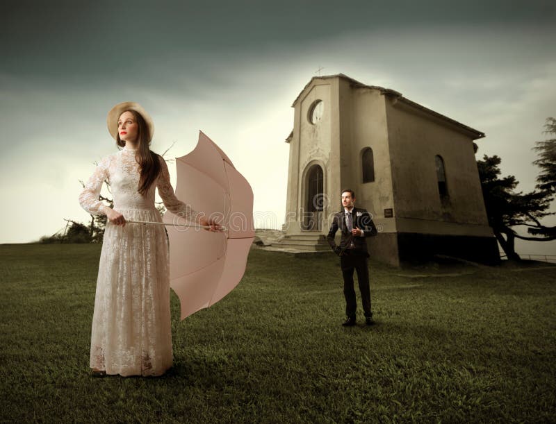 White-dressed woman with umbrella and well-dressed man in front of a church on the background. White-dressed woman with umbrella and well-dressed man in front of a church on the background