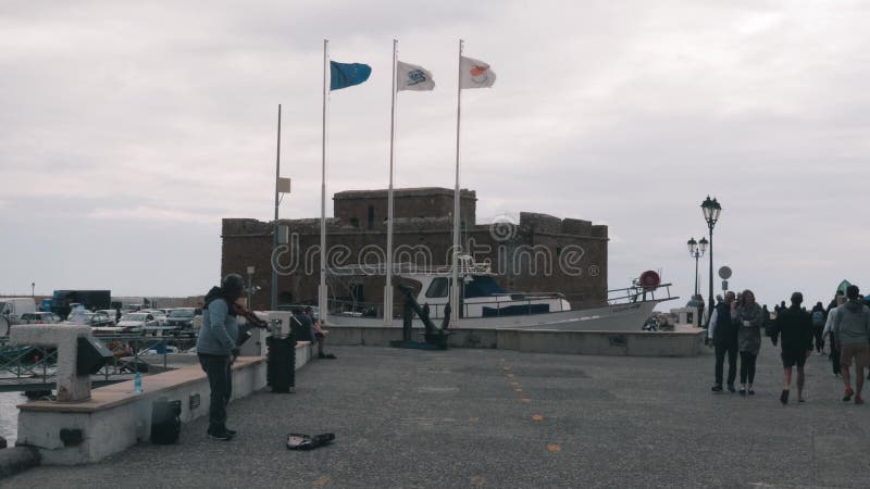 16 mars 2019/Chypre, Paphos. Musicien jouant du violon sur la jetÃ©e. Belle Marina avec chÃ¢teau et gens marchant le long de la je