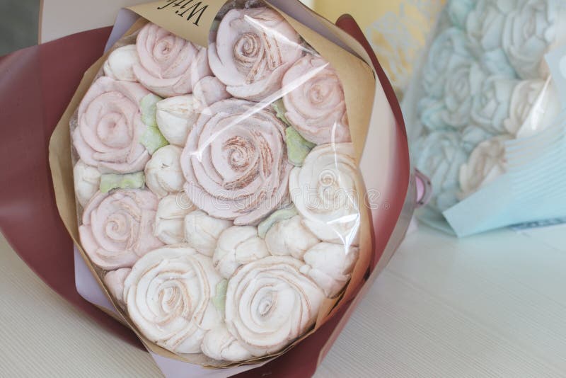 Marshmallow bouquets in craft packaging. Consist of marshmallow roses and tulips. The bouquets lie on the table surface