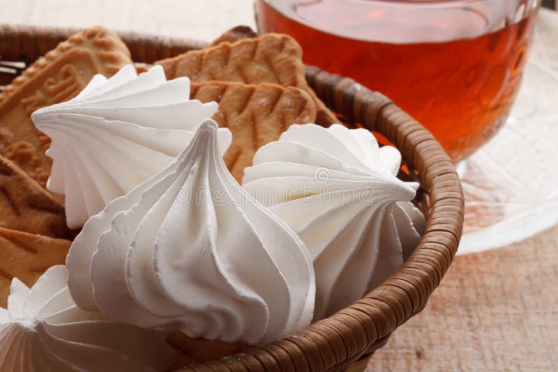 Marshmallows and cookies. In a basket next to a cup of tea royalty free stock images Marshmallows and cookies. In a basket next to a cup of tea royalty free stock images