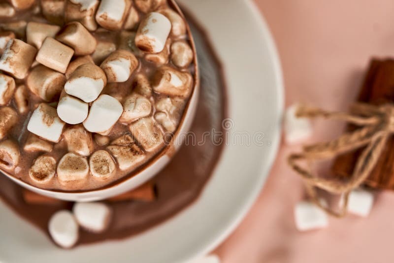 Marshmallows in an overflowing mug with coffee close up, top view