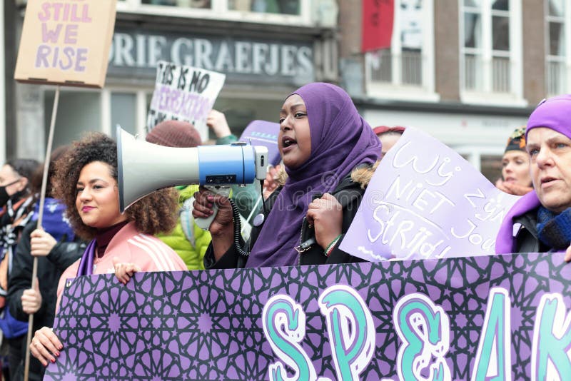 Amsterdam / Netherlands - March 8 2020: Muslim woman marching at Women`s march and screaming in loudspeaker. Amsterdam / Netherlands - March 8 2020: Muslim woman marching at Women`s march and screaming in loudspeaker