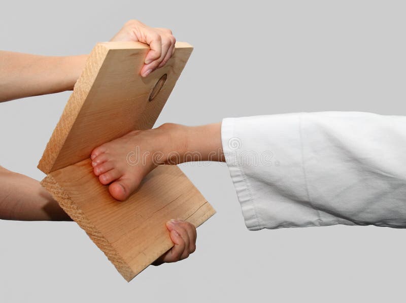 A foot breaking a board held by two hands, isolated in white background. A foot breaking a board held by two hands, isolated in white background.