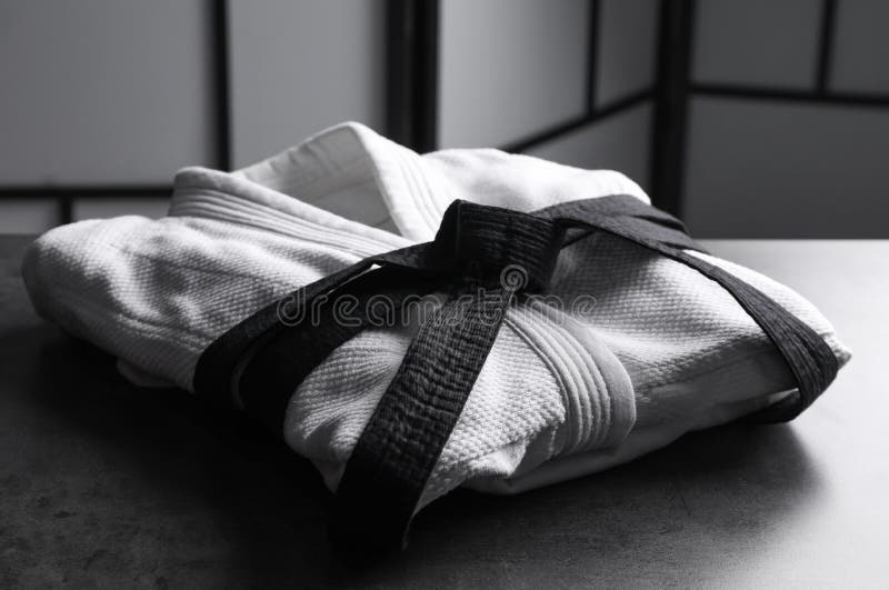 Martial Arts Uniform with Black Belt on Grey Stone Table Indoors Stock