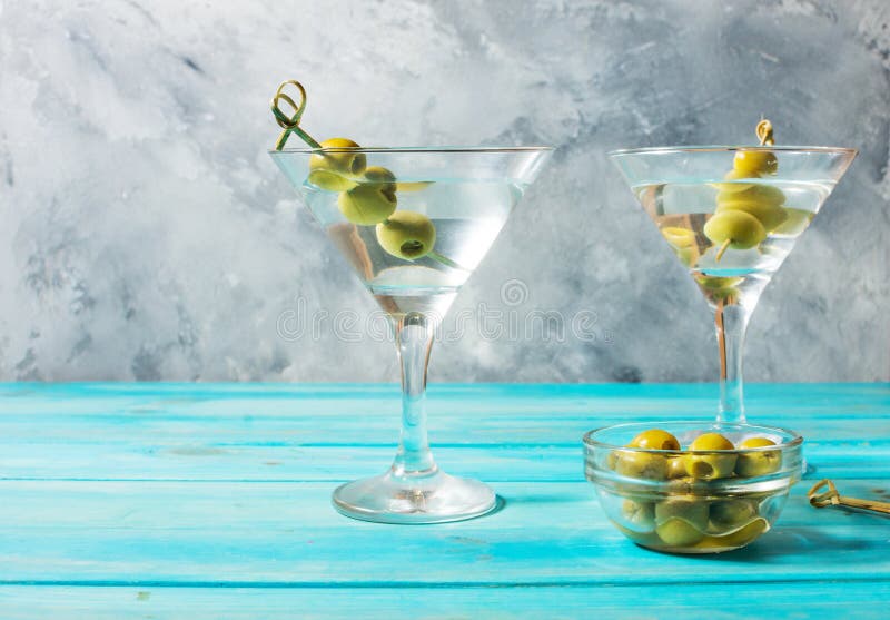 Martini koktajl z zielonymi oliwkami na błękitnym drewnianym tle obrazy stock Martini koktajl z zielonymi oliwkami na błękitnym drewnianym tle obrazy stock