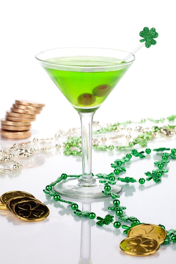 Glass of green Martini for St Patrick's Day surrounded with gold coins and shamrock ornament. Glass of green Martini for St Patrick's Day surrounded with gold coins and shamrock ornament