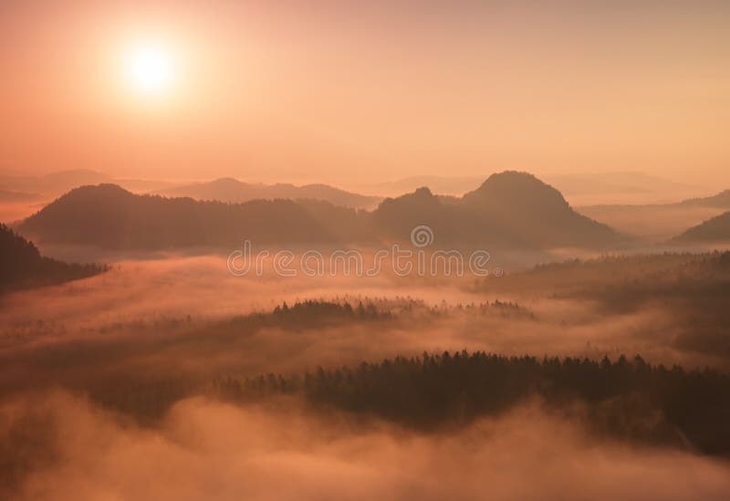 Marvelous red daybreak. Misty daybreak in a beautiful hills. Peaks of hills are sticking out from foggy background, the fog is red