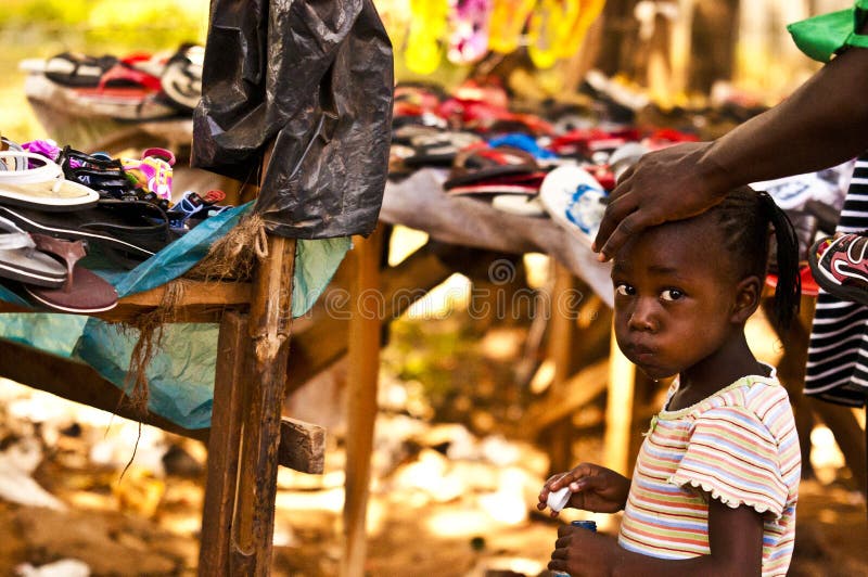 MASAI MARA, KENYA. DECEMBER 18, 2011: A young Kenyan girl at a market with her mother in Mombassa, Kenya. MASAI MARA, KENYA. DECEMBER 18, 2011: A young Kenyan girl at a market with her mother in Mombassa, Kenya.