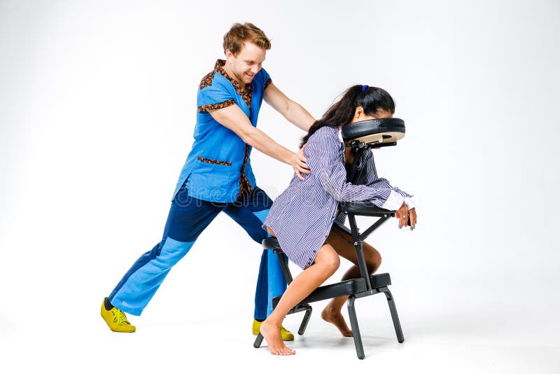 Masaje y oficina del tema Un hombre joven con el terapeuta sonriente en traje azul está haciendo detrás y masaje del cuello para fotografía de archivo Masaje y oficina del tema Un hombre joven con el terapeuta sonriente en traje azul está haciendo detrás y masaje del cuello para fotografía de archivo