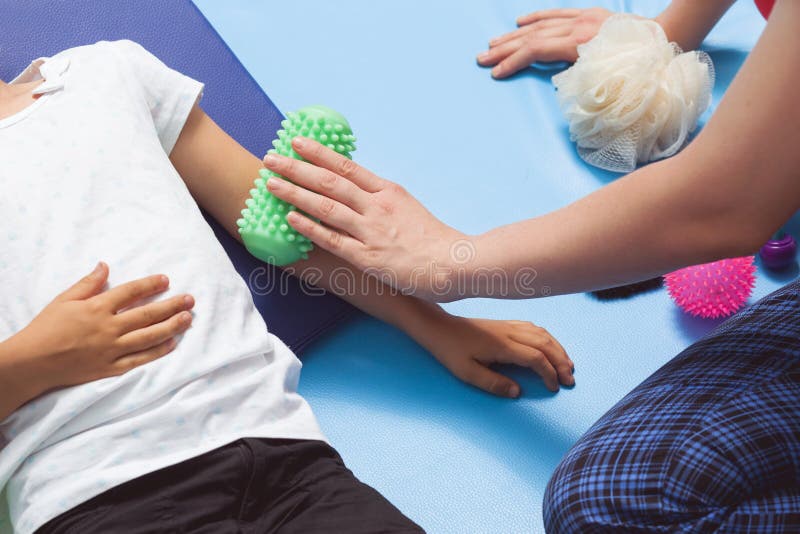 Therapist making a roll massage on young girl's arm. Therapist making a roll massage on young girl's arm