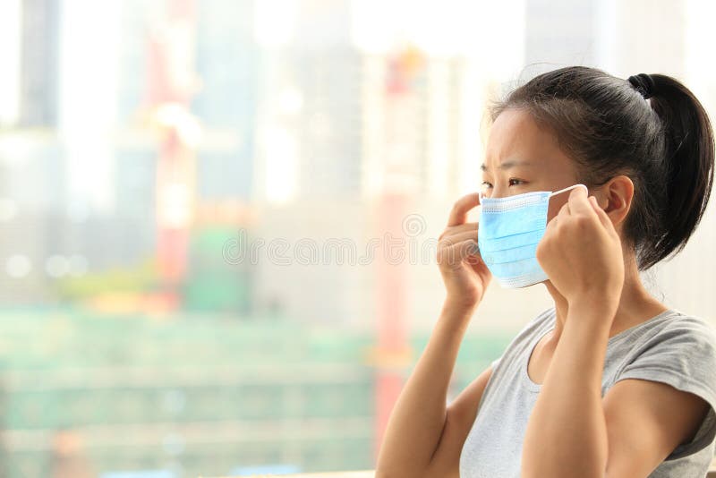 Maschera di protezione asiatica di usura di donna in città fotografia stock libera da diritti Maschera di protezione asiatica di usura di donna in città fotografia stock libera da diritti