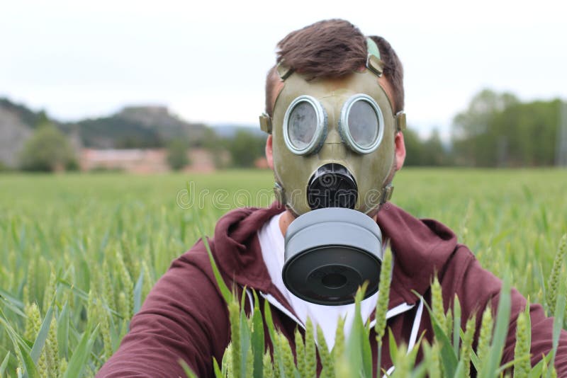 Maschera di respirazione d'uso dell'uomo nel giacimento di grano fotografie stock libere da diritti Maschera di respirazione d'uso dell'uomo nel giacimento di grano fotografie stock libere da diritti