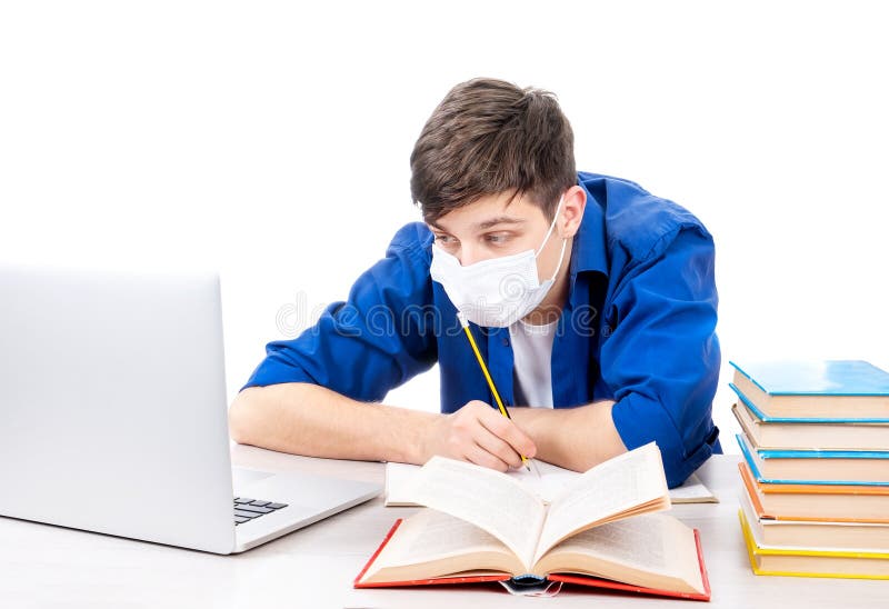 Studente in una maschera per l'influenza con un libro usa un computer portatile sullo sfondo bianco