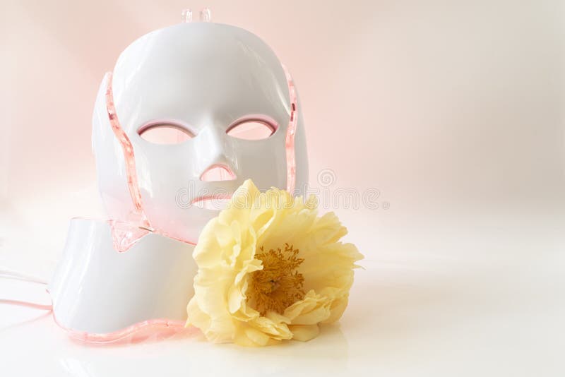 Color therapy mask glowing red with a yellow peony on light background, copy space. Color therapy mask glowing red with a yellow peony on light background, copy space