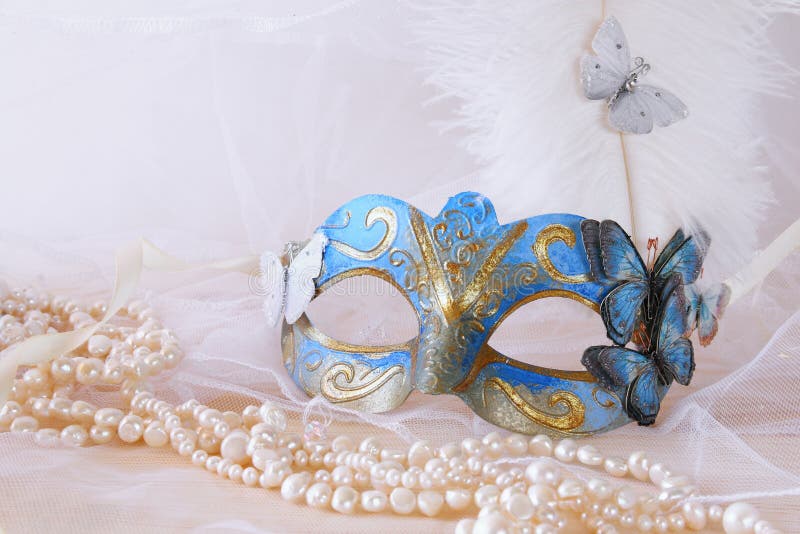 maschera veneziana elegante blu accanto alle perle