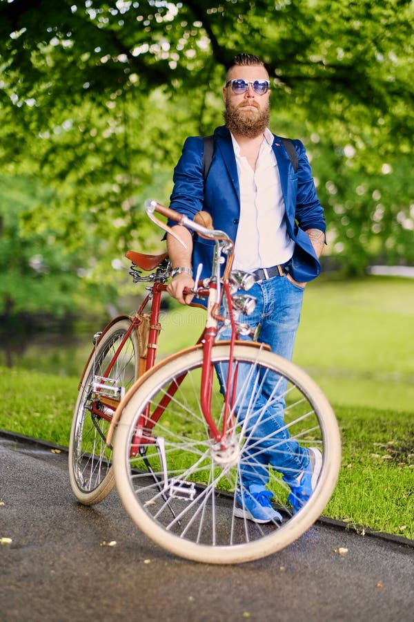 Maschio barbuto della testarossa su una retro bicicletta in un parco fotografia stock Maschio barbuto della testarossa su una retro bicicletta in un parco fotografia stock