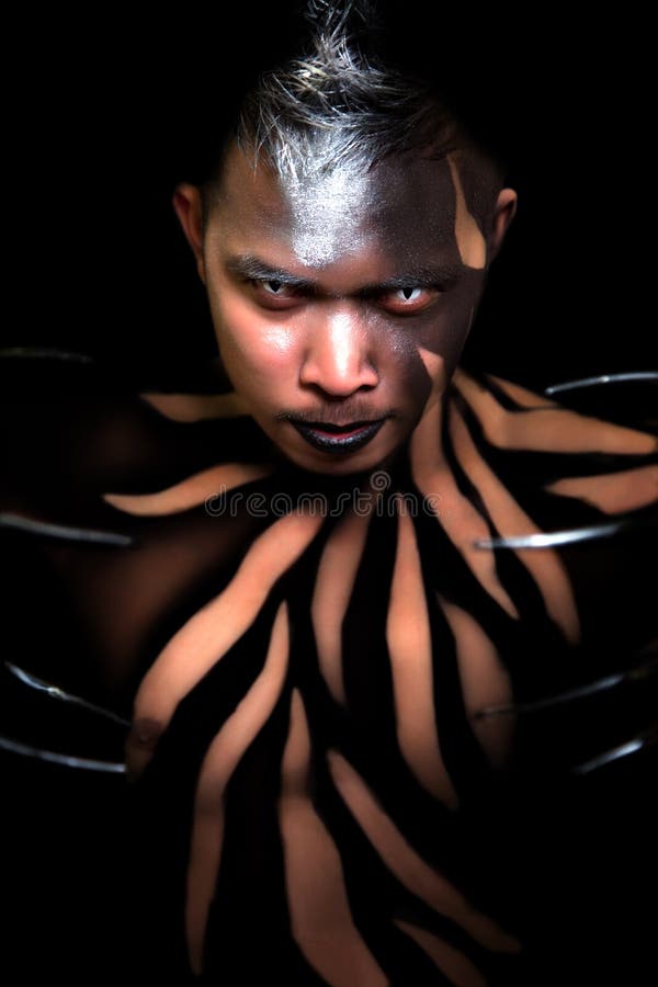 Male with striped body paint wearing long claws cat-like contacts lens. Male with striped body paint wearing long claws cat-like contacts lens