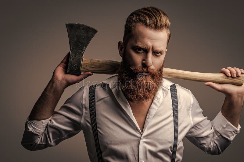 Mascolinità dell'uomo barbuto con un'ascia isolata in grigio. uomo brutale caucasico con barba e baffi. energia maschile fotografia stock