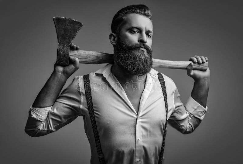 Masculinalità dell'uomo barbuto con un'ascia isolata in grigio. uomo brutale caucasico con barba e baffi. Energia maschile immagini stock