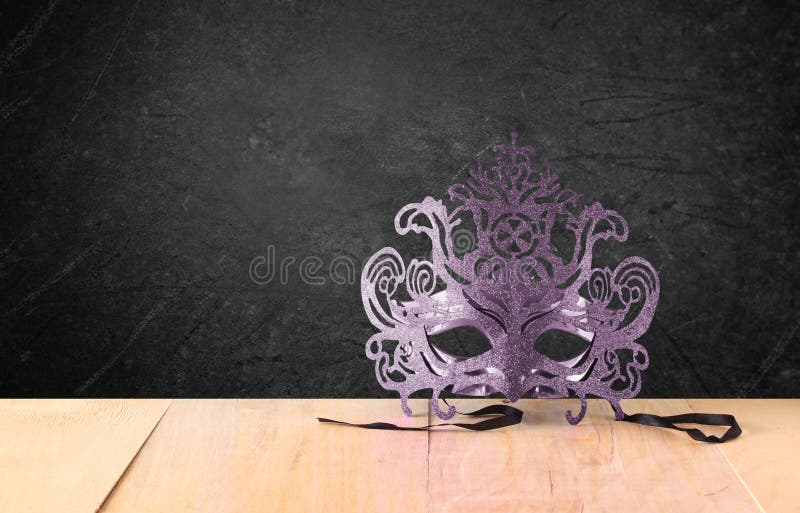 Mască venetiană misterioasă cu peliculă pe masă din lemn și textură pe fond negru royalty free stock image