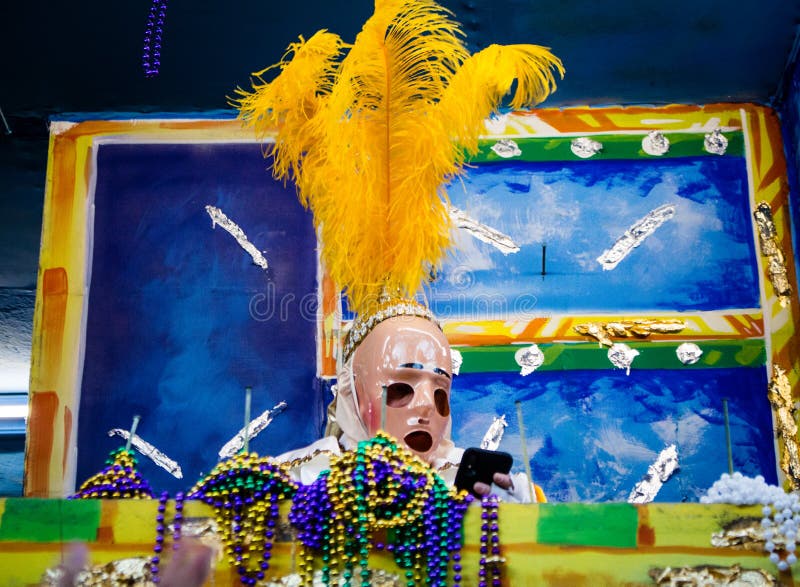 A Masked Krewe Member Checks Their Phone While Riding a Parade Float During Mardi Gras royalty free stock photography A Masked Krewe Member Checks Their Phone While Riding a Parade Float During Mardi Gras royalty free stock photography