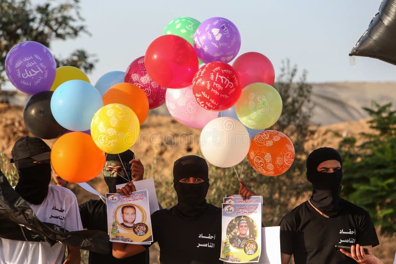 Masked Palestinians of the Popular Resistance Committees prepare incendiary balloons to be flown towards Israel