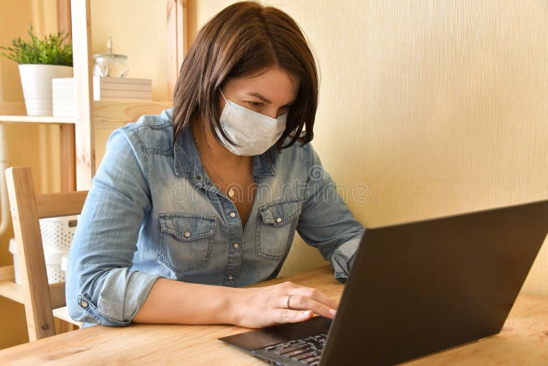 Masked woman works at the computer in a minimalistic interior