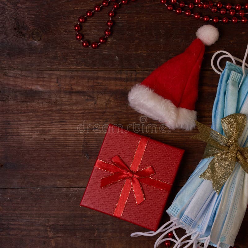 Masken stellen Hut auf Holz Hintergrund dar. Masken und Weihnachtsgeschenksankt-Kappe flatlay mit Raum für Text auf braunem Holz Hintergrund