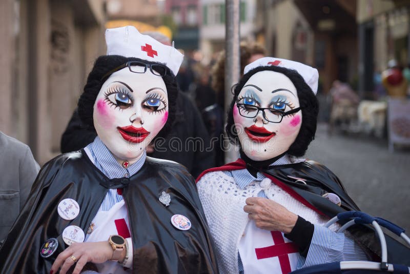 Basel - Switzerland - 9 March 2022 - Portrait of masked women wearing nurse costume parading in the street. Basel - Switzerland - 9 March 2022 - Portrait of masked women wearing nurse costume parading in the street