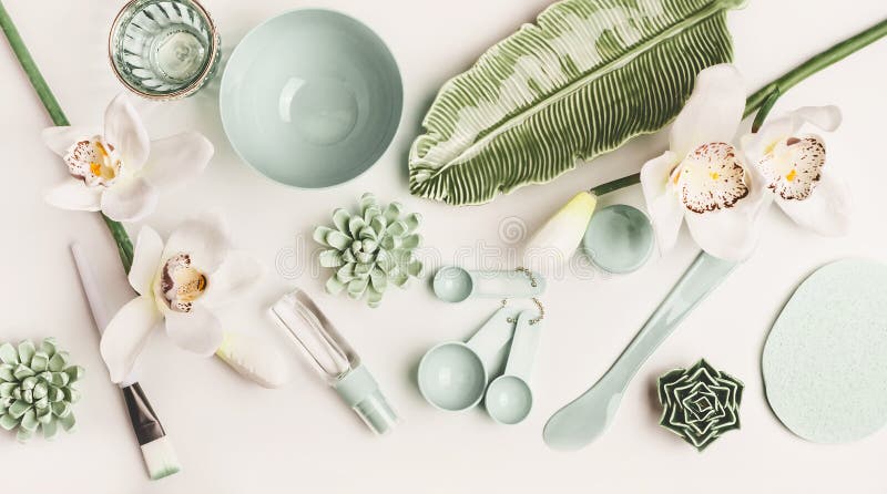 Maskieren Sie Bürste, Schüssel, Spachtel, Messlöffel und Blumen auf weißem Tischplattenhintergrund, Draufsicht stockbild
