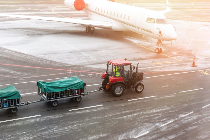 maskin för lastfrakttraktor som levererar bagagevagnar till flygplanet på flygplatsen Flygplatsbärare och service royaltyfri foto maskin för lastfrakttraktor som levererar bagagevagnar till flygplanet på flygplatsen Flygplatsbärare och service royaltyfri foto