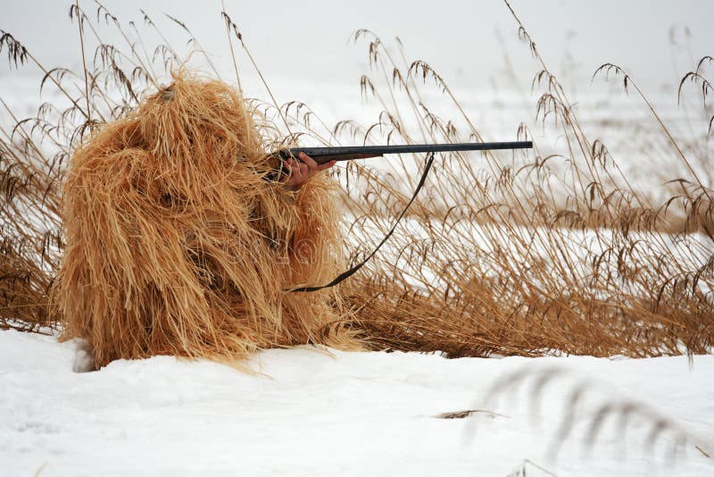 Masking hunter with rifle at spring hunting season