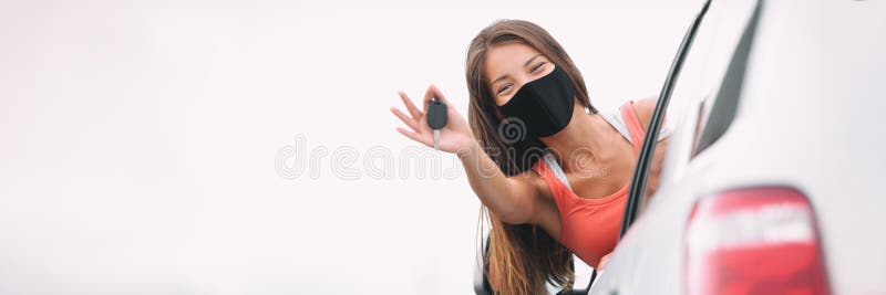 New car happy Asian driver woman wearing face mask for coronavirus showing keys with pride. Drivers license concept panoramic banner. New car happy Asian driver woman wearing face mask for coronavirus showing keys with pride. Drivers license concept panoramic banner.