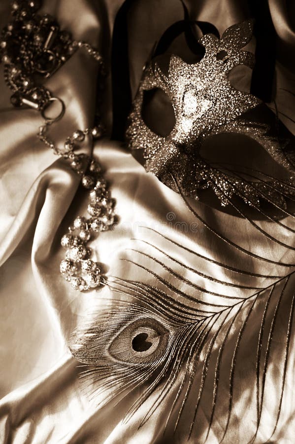 Masquerade mask, beads and feather in sepia