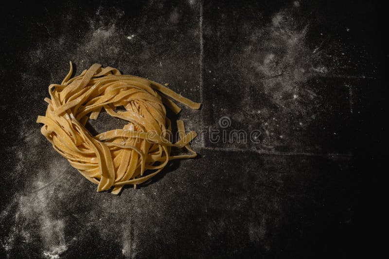 Massa crua isolada em um fundo preto com um lugar para o texto Massa italiana tradicional, macarronetes, tagliatelle Vista superi imagens de stock royalty free Massa crua isolada em um fundo preto com um lugar para o texto Massa italiana tradicional, macarronetes, tagliatelle Vista superi imagens de stock royalty free