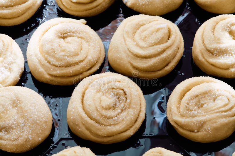 Before going into the oven, the donut dough is sprinkled with sugar and placed in a greased tray. Before going into the oven, the donut dough is sprinkled with sugar and placed in a greased tray