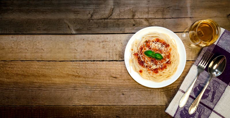 Massa dos espaguetes com vidro de molho de tomate, de queijo, de manjericão e de vinho branco na tabela de madeira Alimento itali imagem de stock Massa dos espaguetes com vidro de molho de tomate, de queijo, de manjericão e de vinho branco na tabela de madeira Alimento itali imagem de stock
