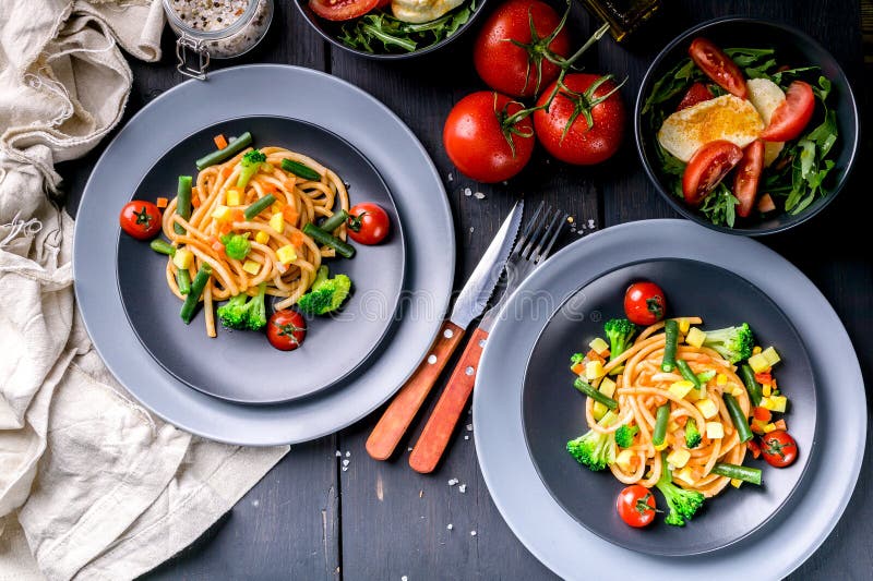 Massa italiana com vegetais e salada com rúcula e mussarela em um fundo de madeira escuro Culin?ria mediterr?nea tradicional fotografia de stock royalty free Massa italiana com vegetais e salada com rúcula e mussarela em um fundo de madeira escuro Culin?ria mediterr?nea tradicional fotografia de stock royalty free