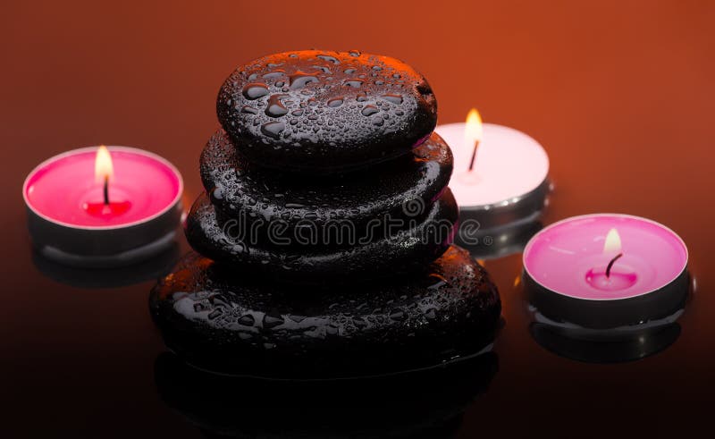 Massage stones with burning candles and water drops