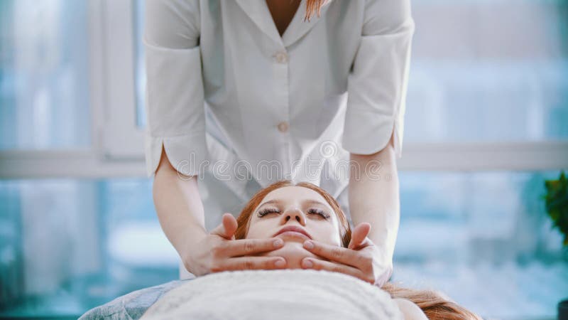 Massage Masseuse Kneading The Forehead Area To A Young Woman Using