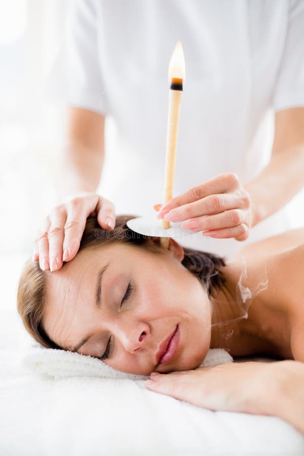 Massaggiatore che dà trattamento della candela dell'orecchio alla donna