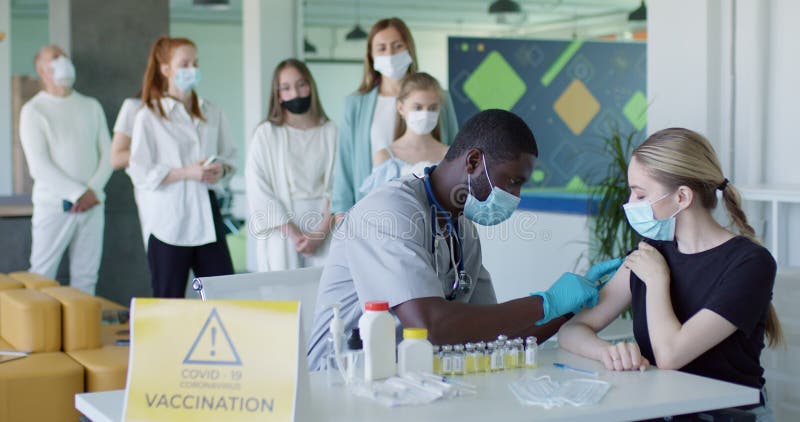 Massale vaccinatie van de bevolking. zwarte mannelijke arts in een masker die antiviraal vaccin gebruikt