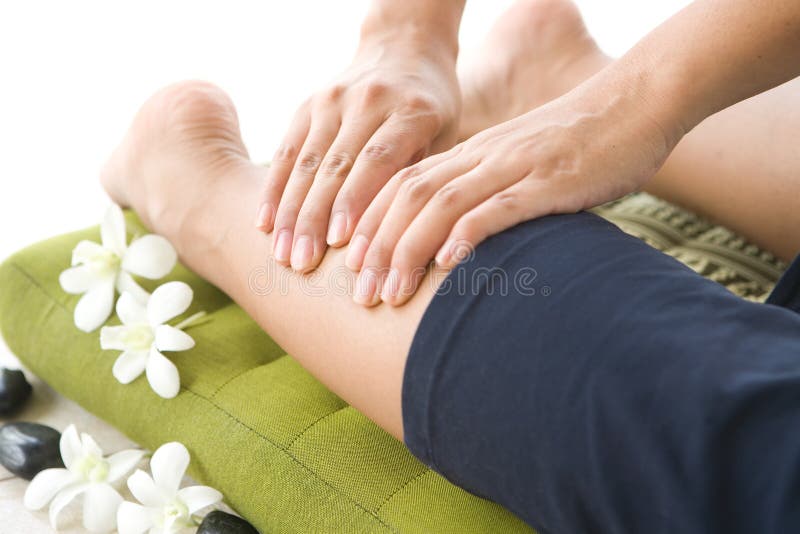 Masseur giving lady patient a leg massage .