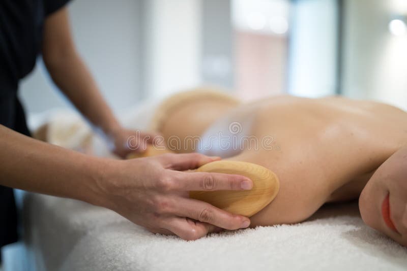 Massez le thérapeute à l'aide de l'outil en bois pour masser le patient photos stock Massez le thérapeute à l'aide de l'outil en bois pour masser le patient photos stock