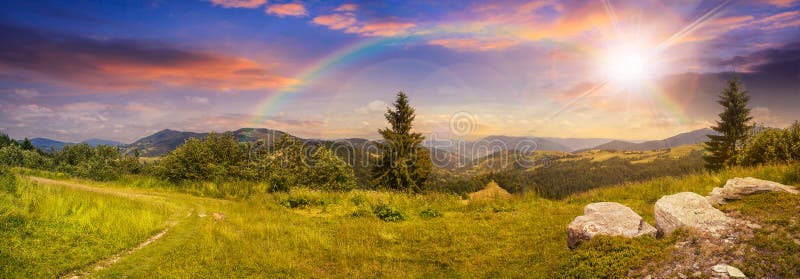 Massi sul prato del pendio di collina in montagna al tramonto con l'arcobaleno